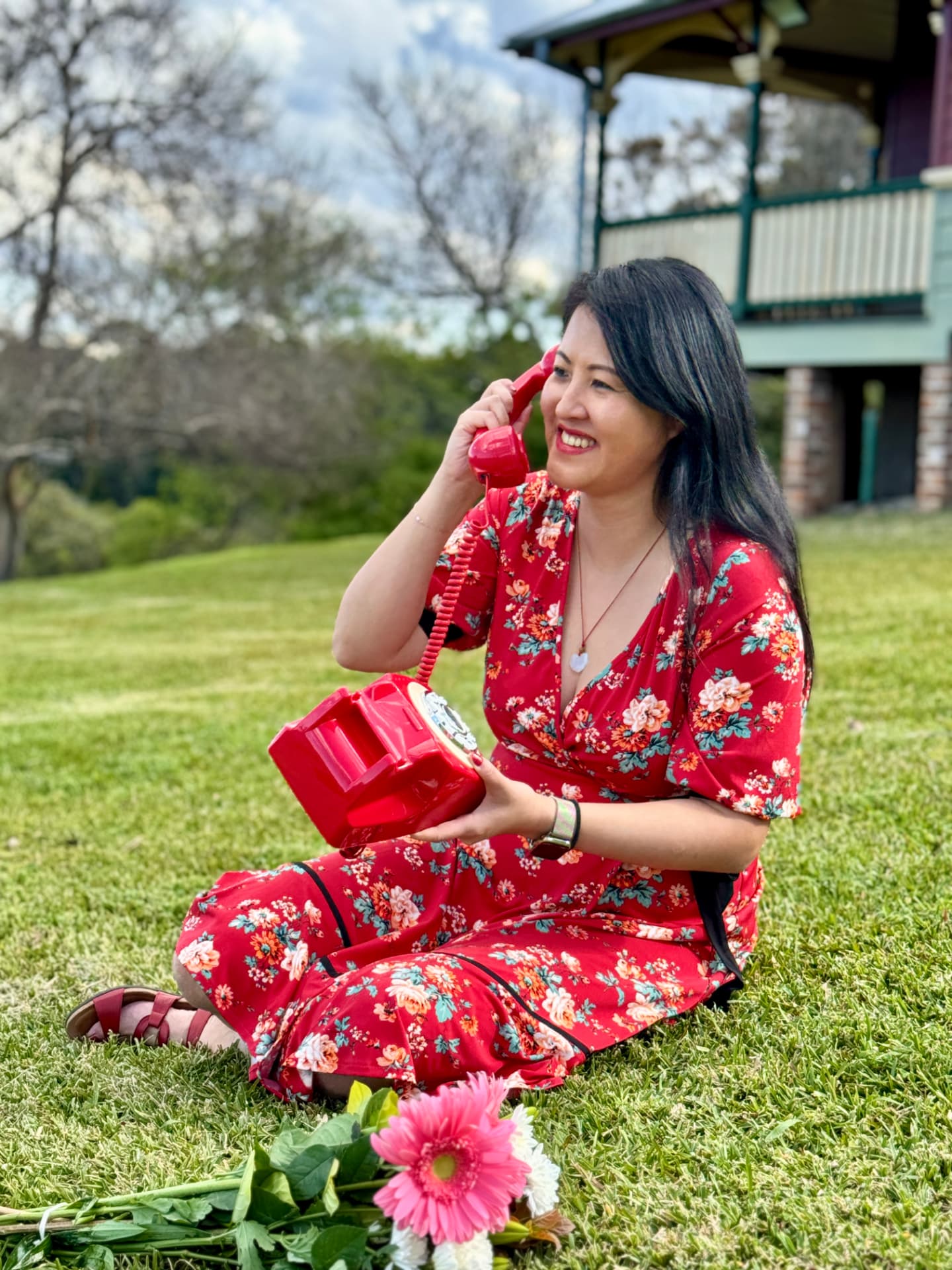 Lucy Lin on a red telephone in a floral dress